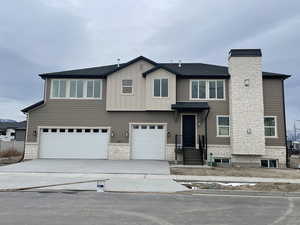 View of front of property featuring stone siding, a garage, concrete driveway, and a chimney