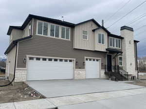 View of front of house with stone siding, a garage, and concrete driveway