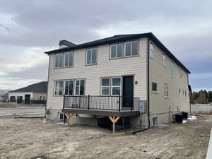Rear view of house featuring a wooden deck and a chimney