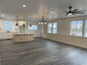 Kitchen featuring open floor plan, a center island, pendant lighting, ornamental molding, and a decorative wall