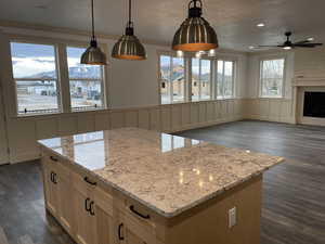 Kitchen featuring dark wood finished floors, light brown cabinetry, decorative light fixtures, a decorative wall, and crown molding