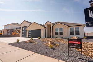 View of front facade featuring a tile roof, driveway, a garage, stone siding, and stucco siding
