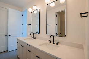 Full bath featuring double vanity and dark tile patterned flooring