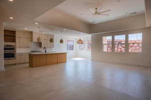 Kitchen featuring open floor plan, a center island with sink, pendant lighting, modern cabinets, and stainless steel double oven