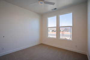 Carpeted spare room with baseboards and a ceiling fan