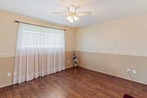 Unfurnished room featuring dark wood-type flooring and ceiling fan