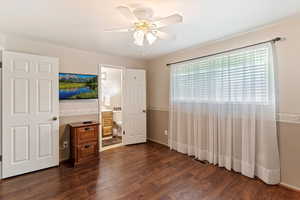 Unfurnished bedroom with dark wood-style flooring, a ceiling fan, and ensuite bath