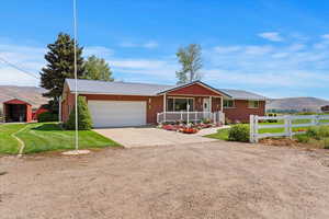 Ranch-style home featuring a mountain view, a porch, driveway, a metal roof, and a garage