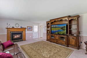 Living area with light colored carpet, a fireplace, and a textured ceiling
