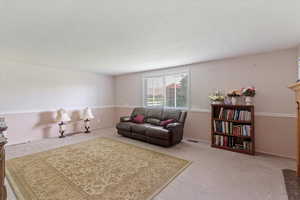 Carpeted living room with a textured ceiling and baseboards