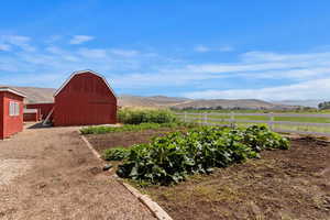 View of yard featuring a mountain view, an outbuilding, a vegetable garden, and a view of countryside