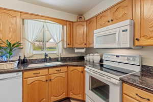 Kitchen featuring white appliances and dark stone countertops