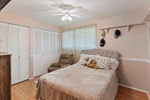 Bedroom featuring multiple closets, light wood-style flooring, and a ceiling fan