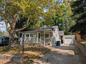 Bungalow-style home featuring a chimney, a garage, and driveway