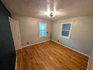 Unfurnished room with wood finished floors and a textured ceiling