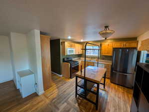 Kitchen featuring stainless steel appliances, light wood-type flooring, a textured ceiling, and light countertops