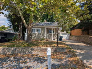 Bungalow featuring a chimney, a garage, concrete driveway, and covered porch