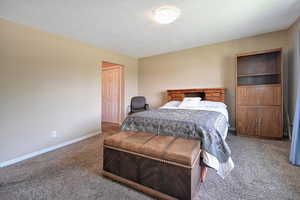 Carpeted bedroom featuring a textured ceiling and a closet