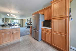 Kitchen with black microwave, open floor plan, light countertops, pendant lighting, and a textured ceiling