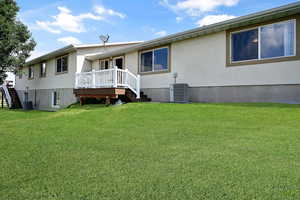 Rear view of house featuring stairway, a yard, stucco siding, and a wooden deck