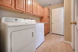 Washroom with washer and clothes dryer and cabinet space