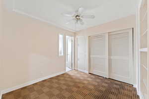 Unfurnished bedroom with dark colored carpet, a closet, and ceiling fan
