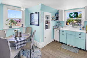 Kitchen featuring light wood finished floors, white cabinets, decorative light fixtures, and blue cabinets