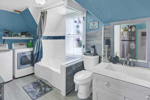 Full bathroom featuring shower / bath combo with shower curtain, vanity, light wood finished floors, independent washer and dryer, and lofted ceiling