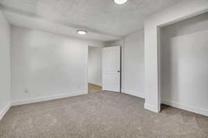 Unfurnished bedroom with a textured ceiling and light colored carpet