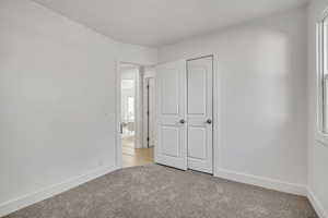 Unfurnished bedroom with light carpet and a closet