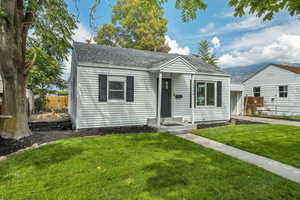 Bungalow with a shingled roof and a chimney