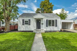 Bungalow-style home with a chimney, roof with shingles, and a carport