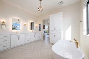 Full bath featuring double vanity, a freestanding tub, and a chandelier