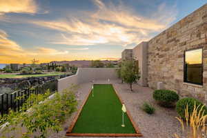 Yard at dusk with a fenced backyard, a putting area, and a mountain view