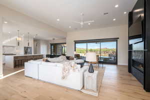 Living area featuring recessed lighting, light wood-type flooring, a glass covered fireplace, and a ceiling fan