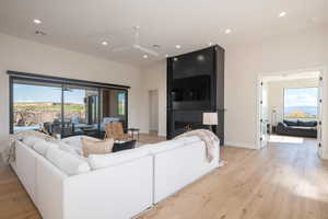 Living area with recessed lighting, light wood-type flooring, a fireplace, and a ceiling fan