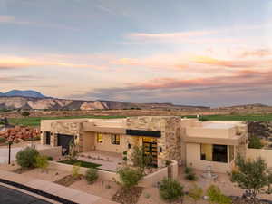 Back of property at dusk with stone siding, a mountain view, stucco siding, and driveway