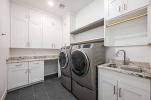 Laundry room featuring cabinet space, washer and dryer, and dark tile patterned floors