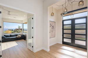 Entrance foyer with french doors, light wood-style floors, and ceiling fan