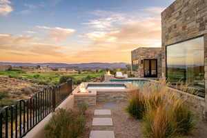 Pool at dusk featuring a patio and a fire pit