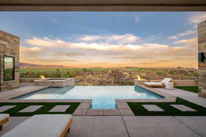 Pool at dusk with a patio and a pool with connected hot tub