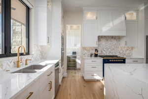 Kitchen with white cabinetry, light stone counters, glass insert cabinets, and wine cooler
