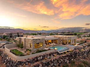 Rear view of property featuring a patio area, a mountain view, stone siding, and a pool with connected hot tub
