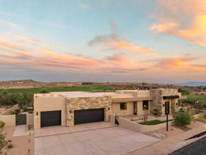 Adobe home featuring a gate, a patio, a garage, stucco siding, and driveway