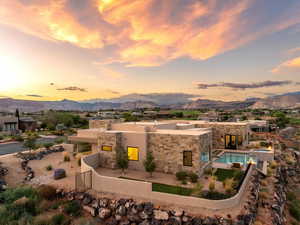 Back of house at dusk with a patio area, a mountain view, stone siding, and stucco siding
