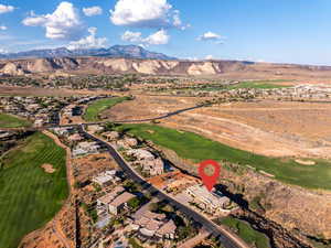 Aerial overview of property's location featuring a mountainous background and a golf course