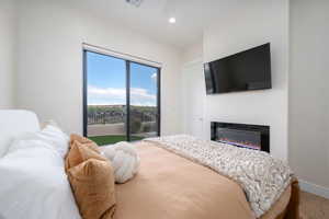 Bedroom featuring access to outside, a glass covered fireplace, recessed lighting, and wood finished floors