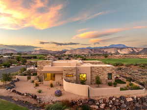 View of front of house featuring a fenced front yard, stucco siding, a mountain view, and stone siding