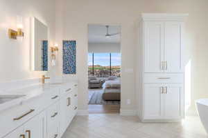 Bathroom featuring double vanity, ensuite bathroom, a freestanding bath, and ceiling fan
