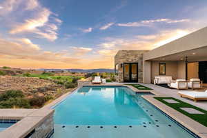 View of pool featuring an infinity pool, a patio, an outdoor living space, and a mountain view